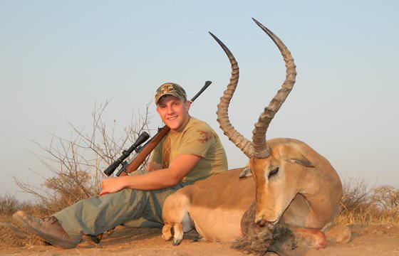 A proud hunter relaxes next to his impala trophy.
